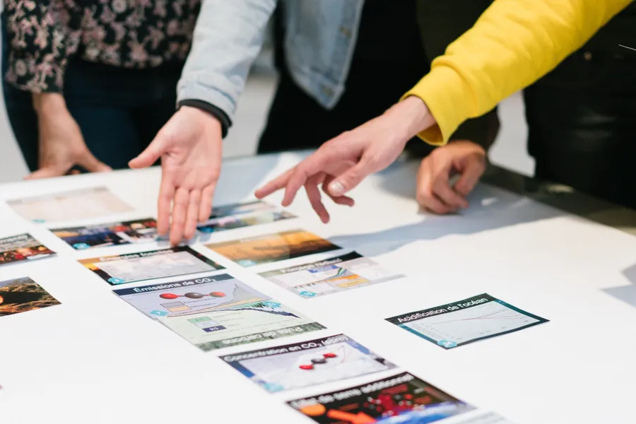 Mains plaçant des cartes sur la table pendant la Fresque du climat