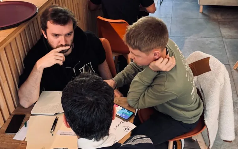 Joueurs penchés sur une feuille du jeu Le partage d’Orion